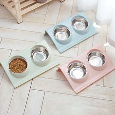 three bowls with food in them sitting on the floor next to a dog bowl and water dish