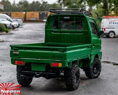 a green pick up truck parked in a parking lot