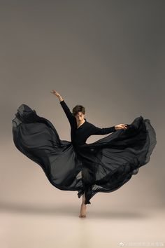 a woman in black is dancing on a gray background