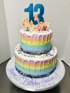 a birthday cake with rainbow icing and sprinkles on it is displayed