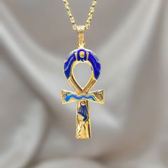 an egyptian cross necklace with blue and gold accents on a white cloth background in the foreground