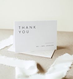 a thank you card sitting on top of torn up white paper with the words, thank you