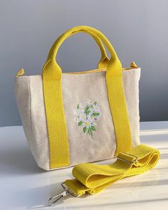 This stylish women's linen bag offers a design that is both elegant and functional. The outer surface of the bag is decorated with eye-catching daisy embroidery and offers a natural look. These daisy embroideries add elegance and naturalness to the bag, while also adding a bohemian touch to your style. Two pocket compartments inside allow you to store your personal belongings in an orderly manner. These pockets allow you to easily find your daily items, such as your phone, wallet or make-up. The Spring Embroidered Cotton Shoulder Bag, Embroidered Canvas Bag For Everyday Spring Use, Spring Canvas Bag With Removable Pouch And Double Handle, Spring Cotton Shoulder Bag With Floral Embroidery, Embroidered Beige Canvas Bag, Spring Yellow Canvas Bag For Daily Use, Handmade Spring Canvas Tote Bag, Spring Canvas Beige Bag, Spring Canvas Rectangular Bag