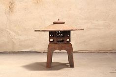 an old metal object sitting on top of a cement floor next to a white wall