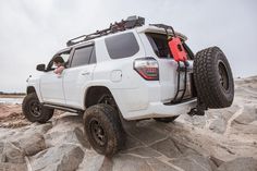 a white four - door toyota truck parked on some rocks