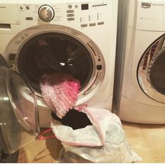 a pile of clothes sitting inside of a washing machine next to a dryer and washer