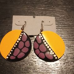 a pair of pink and yellow earrings with dots on them sitting on top of a wooden table