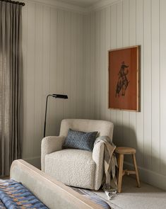 a living room with a chair, lamp and painting on the wall in it's corner