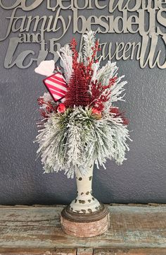 a vase filled with red and white flowers sitting on top of a wooden table next to a sign