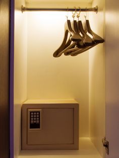 a bunch of shoes hanging from hooks in a closet next to a remote control box