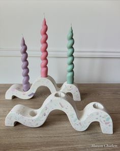 three candles sitting on top of a wooden table next to each other in different colors