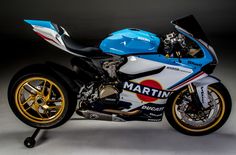 a blue and white motorcycle parked on top of a gray floor next to a black wall