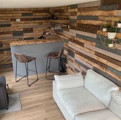 a living room filled with furniture next to a wooden wall covered in wood planks