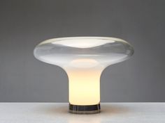 a glass table lamp sitting on top of a white counter next to a gray wall