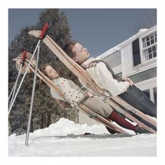 a man and woman sitting on skis in the snow next to each other,