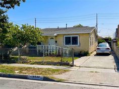 a car parked in front of a house with a chain link fence around the yard