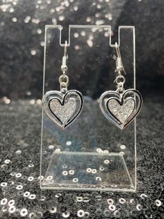 Black and silver heart earrings with rhinestones filling the center. Silver Double Heart Earrings, Heart-shaped Rhinestone Earrings For Anniversary, Silver Open Heart Earrings For Party, Crystal Heart-shaped Earrings For Pierced Ears, Silver Heart Cut Metal Earrings, Silver Heart Jewelry With Bling, Silver Heart Pierced Earrings For Party, Silver Sparkling Heart Earrings, Silver Sparkling Heart-shaped Earrings