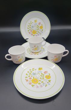 four plates and two cups with flowers on them