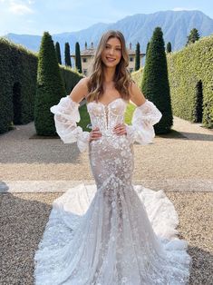 a woman in a wedding dress posing for the camera with her hands on her hips