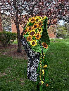 a crocheted sunflower scarf hanging from a tree