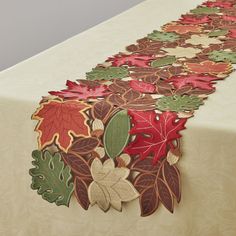 an image of a table setting with leaves on the table cloth and placemats