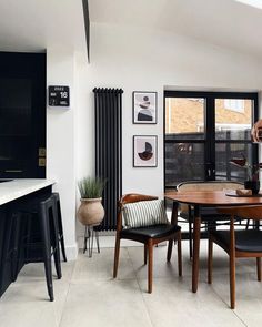 a dining room table with chairs and pictures on the wall behind it, along with other furniture