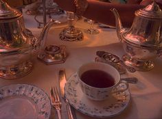 there is a tea set on the table with silverware and cups in front of it