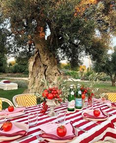 an outdoor table set for two with red and white striped napkins, plates and glasses