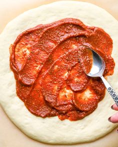 someone is spreading sauce on top of a pizza dough