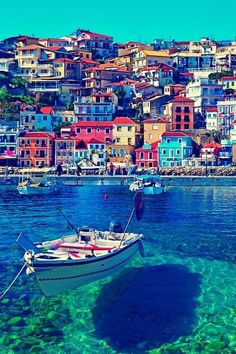 a boat floating on top of a body of water next to a city covered in colorful buildings