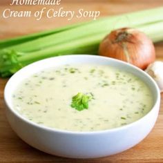 a white bowl filled with cream of celery soup next to an onion on a cutting board