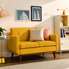 a living room with a yellow couch and some pictures on the wall next to it