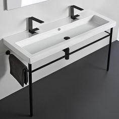 a white sink sitting under a bathroom mirror next to a black metal stand with two faucets on it