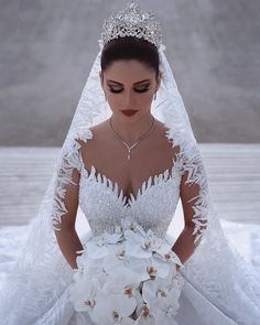 a woman in a wedding dress holding a bouquet of flowers and wearing a tiara