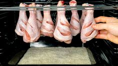 bacon hanging from the rack in an oven with someone's hand reaching for it