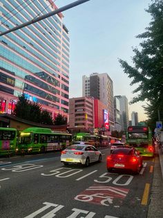 cars are driving down the street in front of tall buildings with neon signs on them