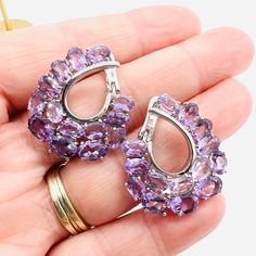 Gorgeous Estate Fresh Large Sterling Silver 11.2ct Amethyst Earrings. Sterling silver metal set with 28 amethyst gemstones in an unusual hoop like design. Fully marked and acid tested as sterling silver. All stones tested and guaranteed. These are lever backs for pierced ears. Which are secure. Excellent condition with minimal age appropriate wear. Measure just over 1 1/8 inches long by 1 inch wide. 9.7gm. Lavender Gemstone Earrings Fine Jewelry, Luxury Vintage Amethyst Jewelry, Luxury Silver Amethyst Earrings, Luxury Teardrop Amethyst Earrings, Luxury Amethyst Gemstone Earrings, Purple Tanzanite Gemstone Earrings, Purple Sterling Silver Earrings, Fine Jewelry, Silver Amethyst Earrings With Multi-stone, Vintage Amethyst Purple Earrings