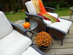 two chairs and a table on a deck with flowers in the basket next to them