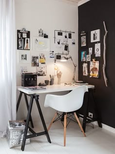 a white desk sitting under a window next to a wall covered in pictures and photos