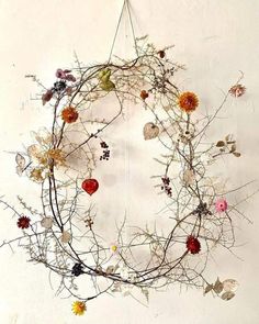 an arrangement of dried flowers and leaves arranged in a circular shape on a white wall