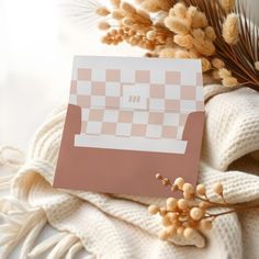 a piece of paper sitting on top of a blanket next to dried flowers and plants