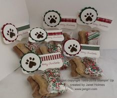 several dog treats are wrapped in plastic and decorated with holiday themed ribbons, bows, and paw prints