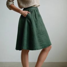 a woman is wearing a green skirt and white shirt with her hands on her hips