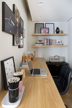 a laptop computer sitting on top of a wooden desk next to a book shelf filled with books