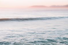 a man riding a wave on top of a surfboard in the ocean at sunset