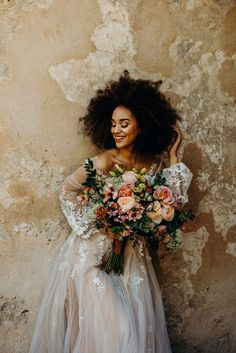 a woman in a wedding dress holding a bridal bouquet with her hair blowing back