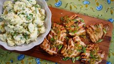 chicken and mashed potatoes on a wooden cutting board next to a bowl of salad