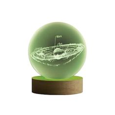 a green glass ball sitting on top of a wooden stand with an image of saturn in the center