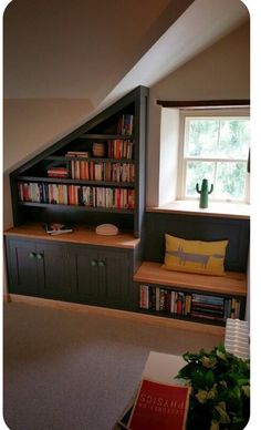 a room with bookshelves, cabinets and a window in the corner is shown