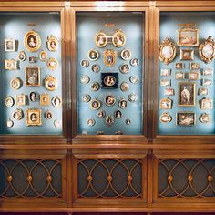 a display case filled with lots of different types of framed pictures on glass walls and wood trimmings